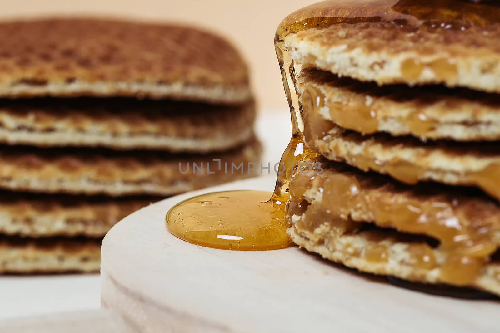 Close-up of honey pouring over some waffles on a wooden tray