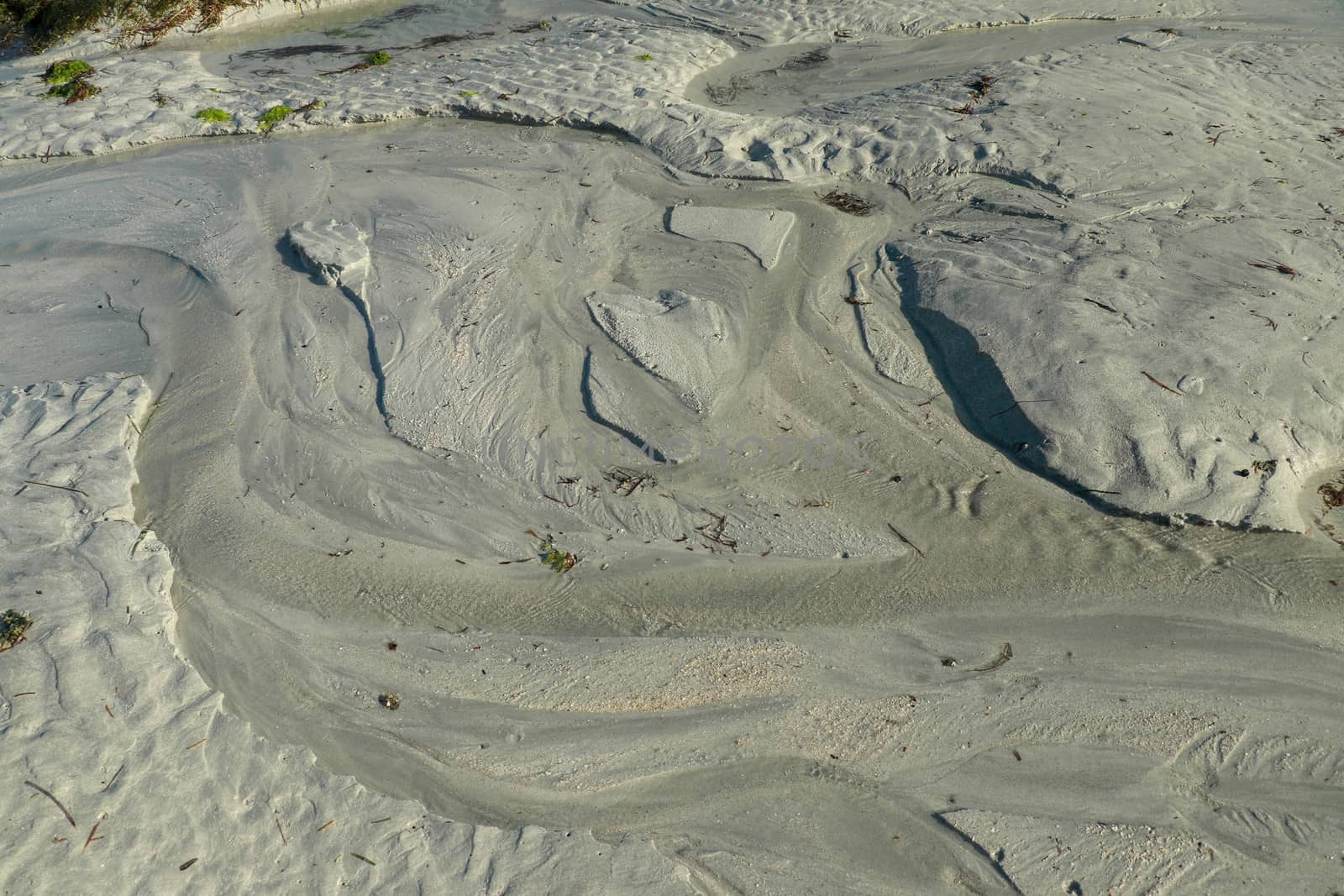 Sandy beach in Wells next the Sea. The tide has just gone out and the beach is muddy with sea water.