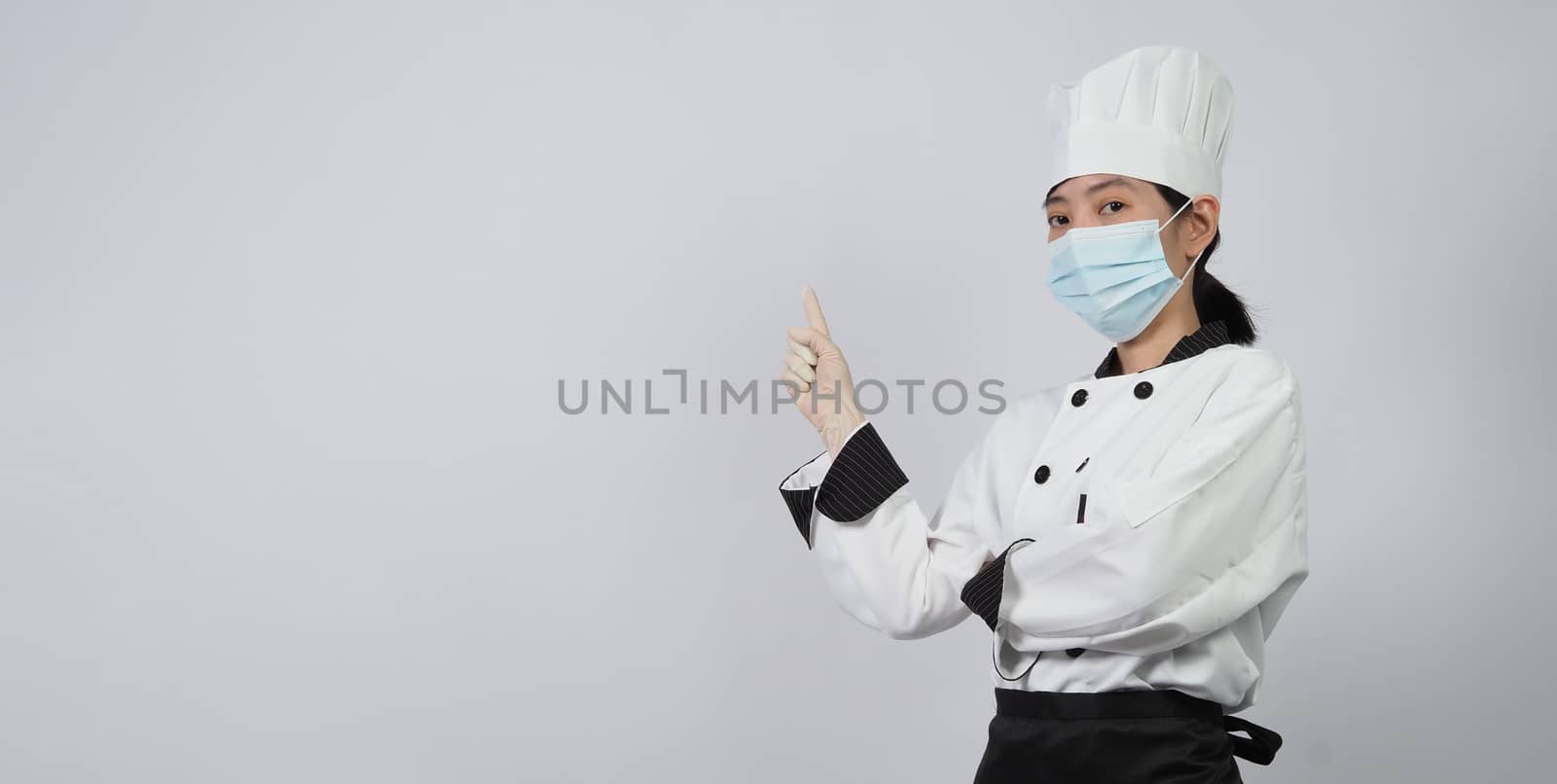 Asian woman chef in uniform with medical face mask and glove. by gnepphoto