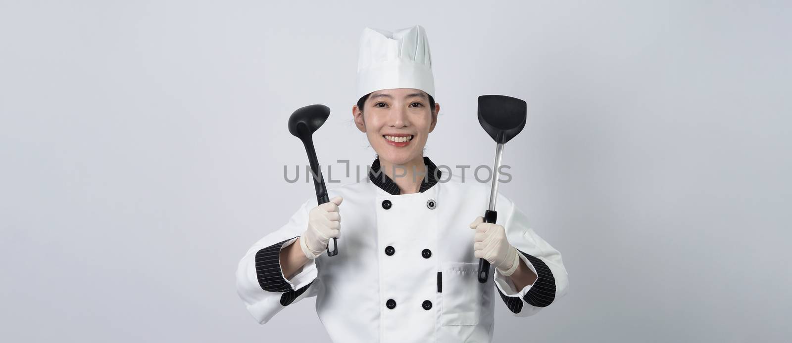 Middle aged of asian woman chef holding smartphone or digital tablet and received order from online shop or merchant application. she smiling in chef uniform and standing in studio with white color background.