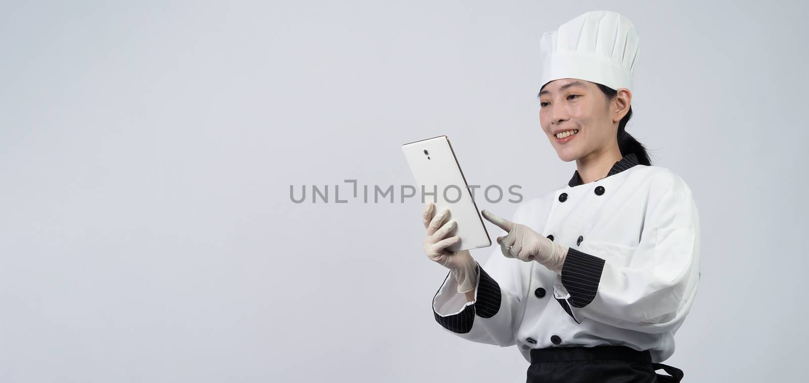Asian woman chef holding tablet and received order from online s by gnepphoto