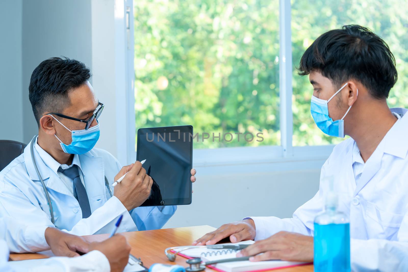 Group of doctor wearing protective surgical mask and discussing work together at the table during meeting at hospital,Epidemic virus outbreak concept.