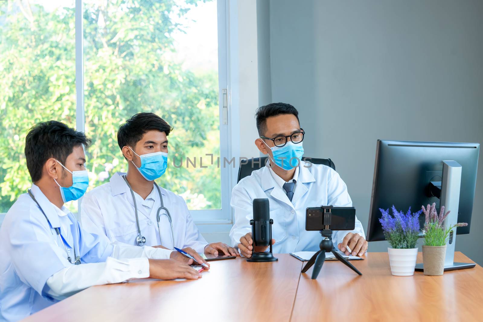 Group of doctor wearing protective surgical mask discuss work together and looking at online presentation on computer at hospital.