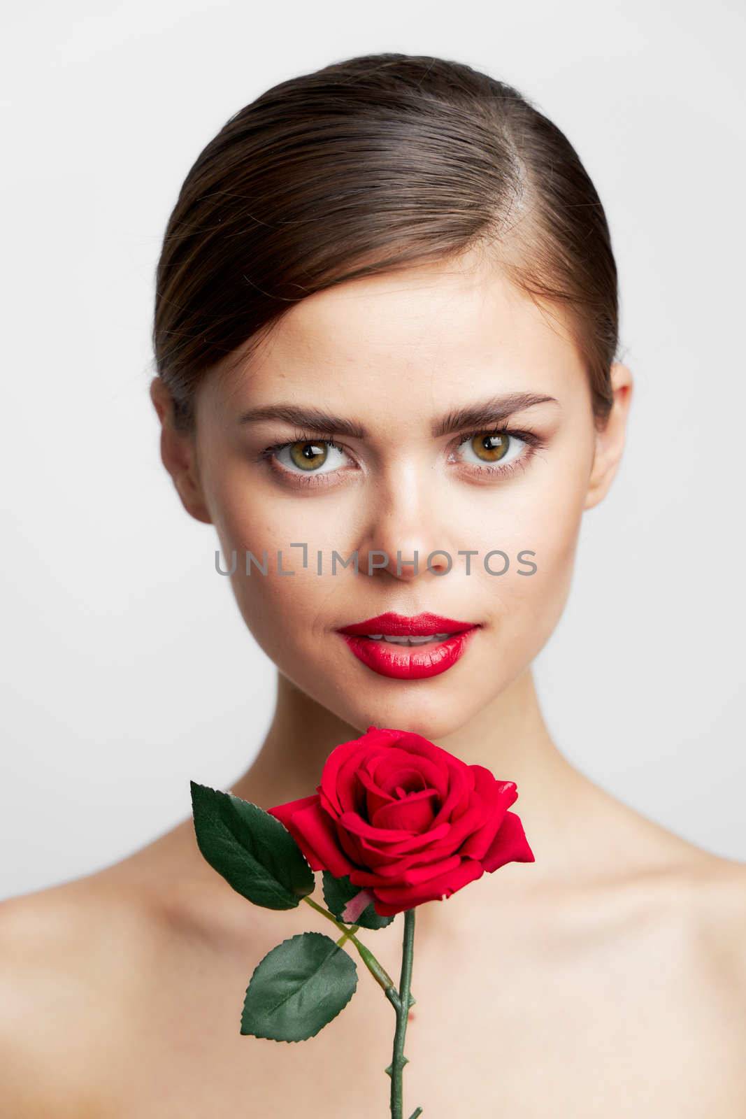Woman with bare shoulders With a flower in her hands, a charm model red lips close-up