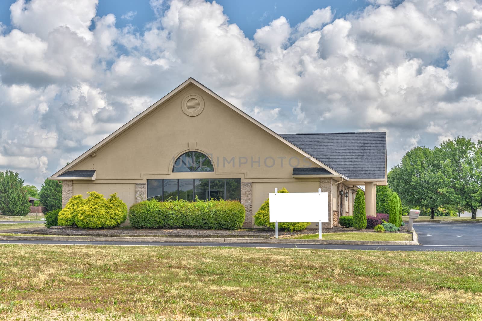 Horizontal shot of a bankrupt commercial building complex with a blank white sign next to it.