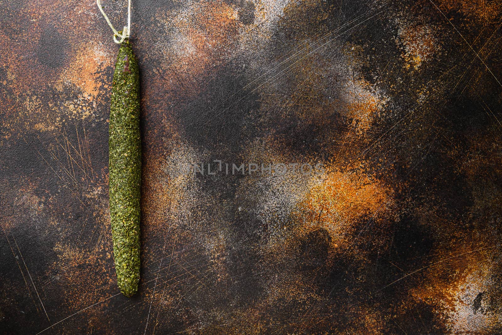 Spanish dry salami fuet in herbs on old metall background with space for text.