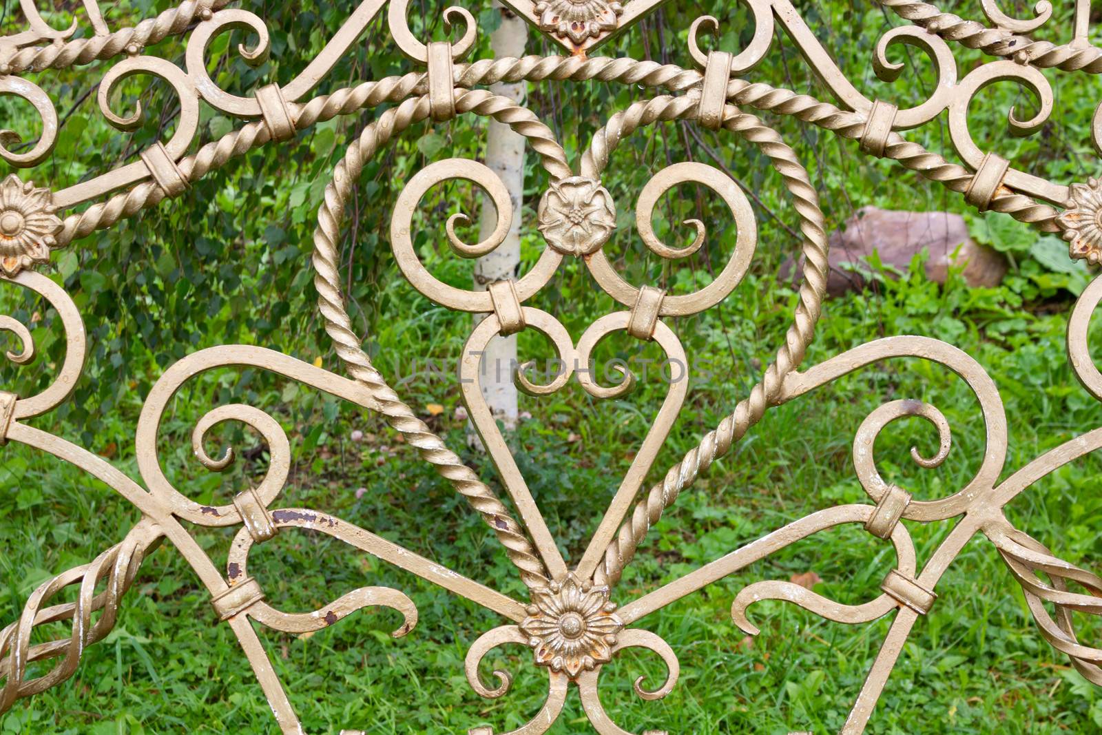 Forged elements on a garden bench in the shape of a heart.Garden wrought iron furniture in the garden.