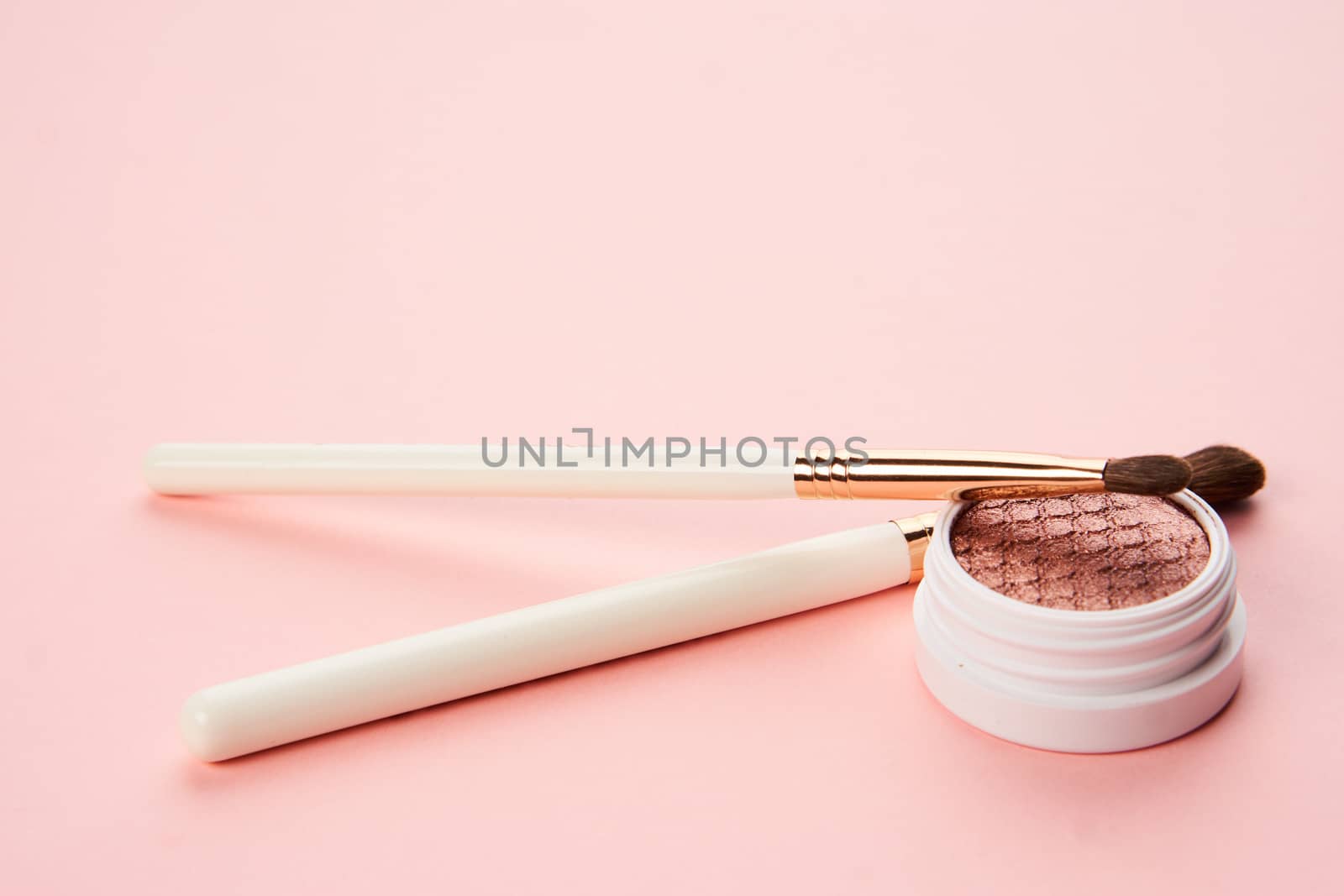 makeup brushes and eyeshadow professional cosmetics on pink background by SHOTPRIME