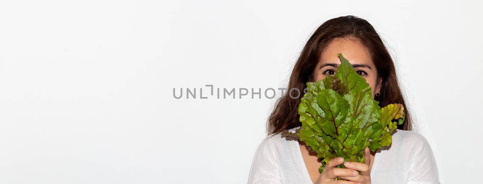Real young man with a bunch of radishes covering his face. Isolated on a white background. by leo_de_la_garza