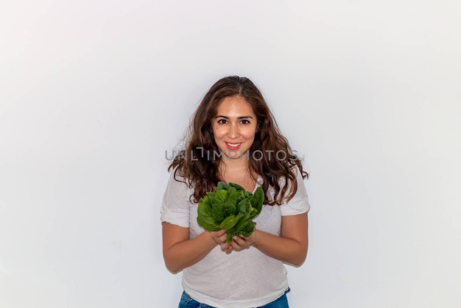 Real young man with a bunch of spinach. Isolated on a white background. by leo_de_la_garza