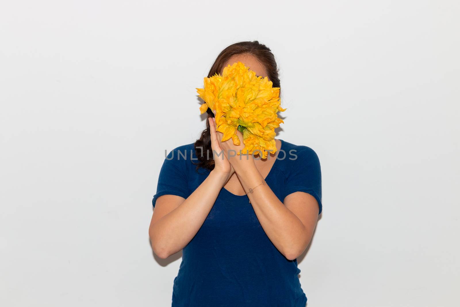 Real young man with a bunch of pumpkin flower covering his face. Isolated on a white background. by leo_de_la_garza