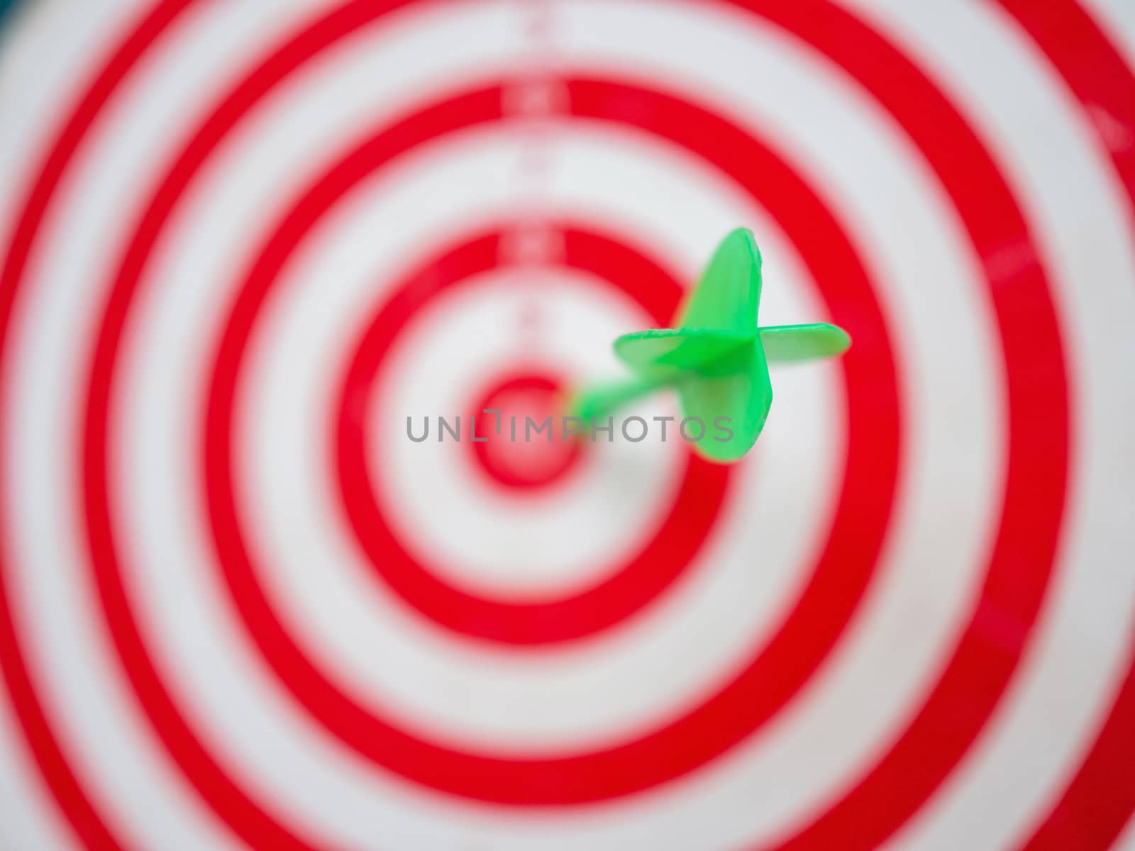 Green arrow strikes center of goal on blurred background - Successful business goal idea.
