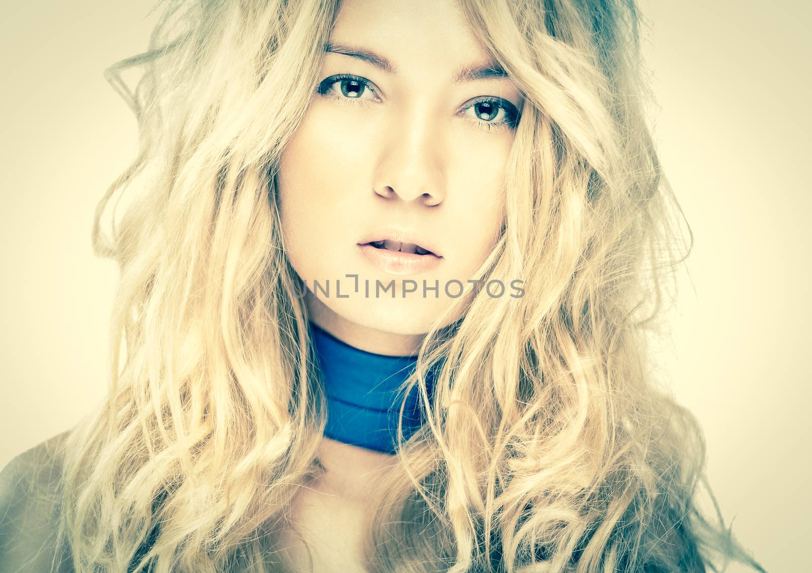 Pretty blonde looking in camera. Beautiful model with perfect skin and wild hairstyle. Attractive young woman with confident look. Sexy face expression of glamorous girl. Gentle and elegant female.