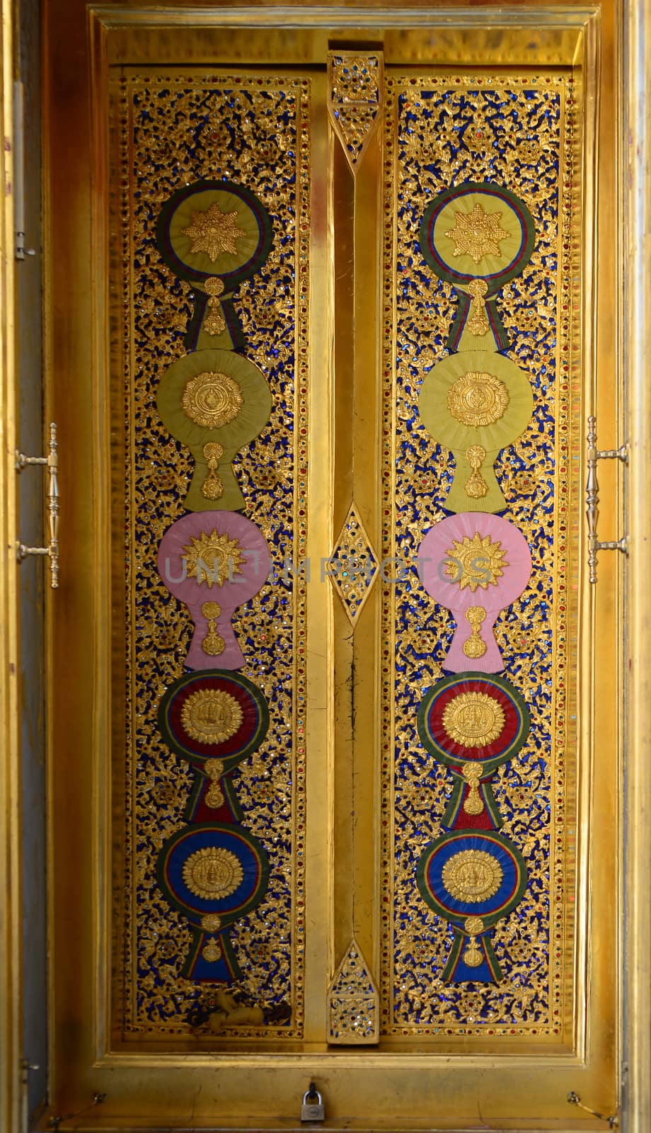 the wood carving door panels with painted royal insignias on a door panel, among flowery patterns, appear the first classes of each insignia category at Wat Ratchabophit, Bangkok, Thailand