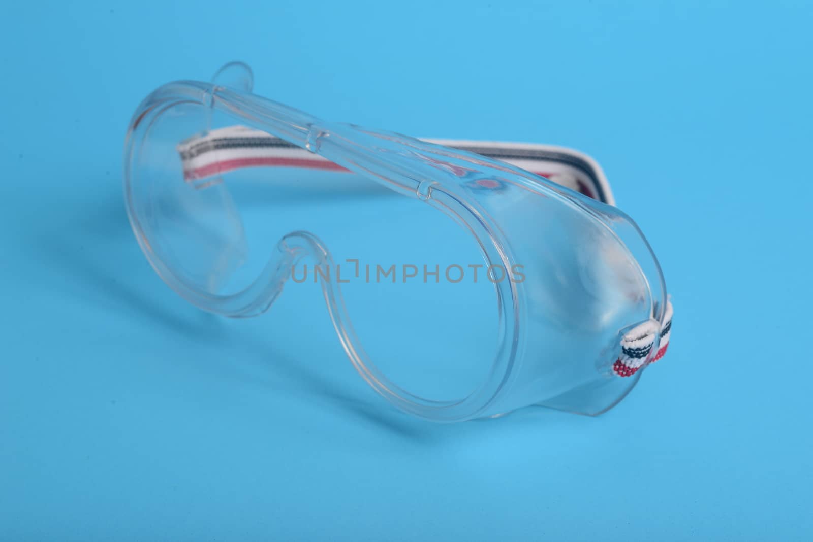transparent plastic laboratory glasses on blue background by ideation90