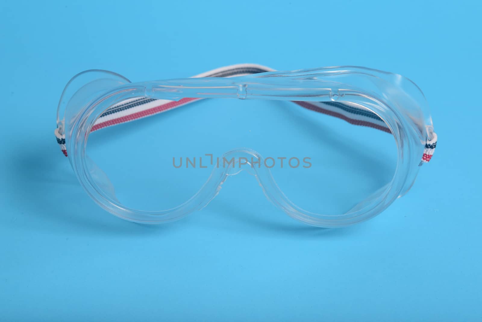 transparent plastic laboratory glasses on blue background by ideation90