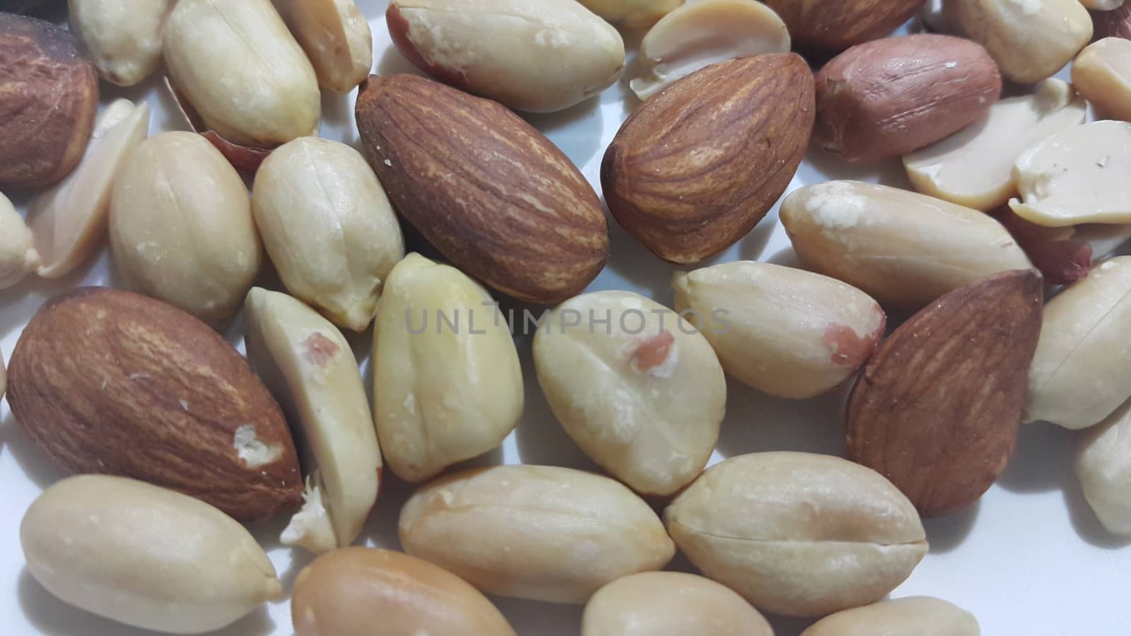 Closeup view of mixed dried and roasted  peanuts and almonds. A fruit for background text