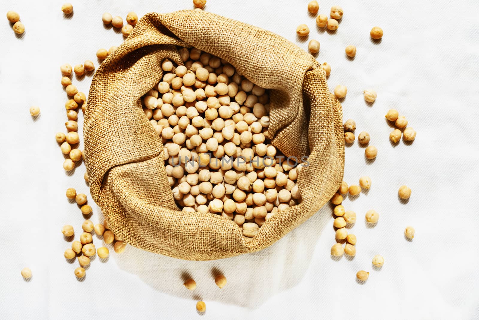 Beautiful bunch of brown chickpea into a cotton bag , on the white background several chickpea