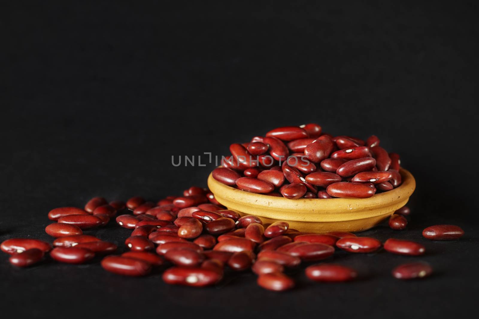 Common red beans -kidney bean - on black background , part of the beans are in a bowl