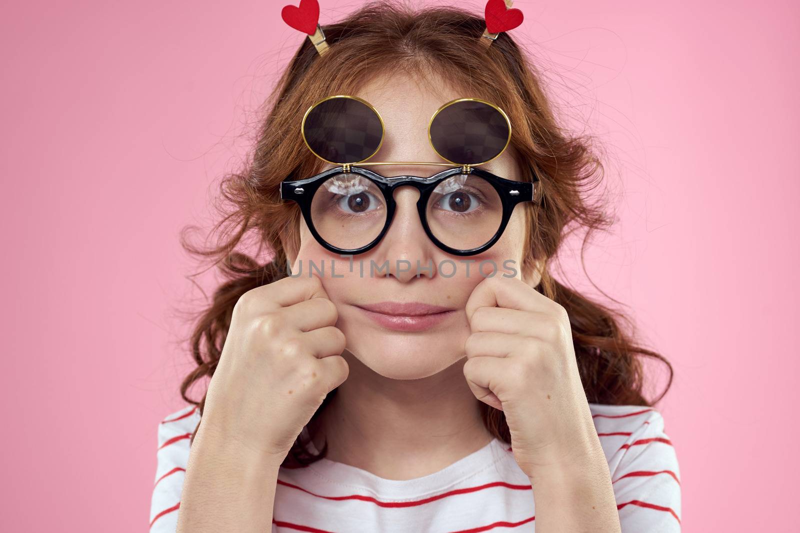 Cheerful girl with pigtails sunglasses striped t-shirt lifestyle pink background. High quality photo