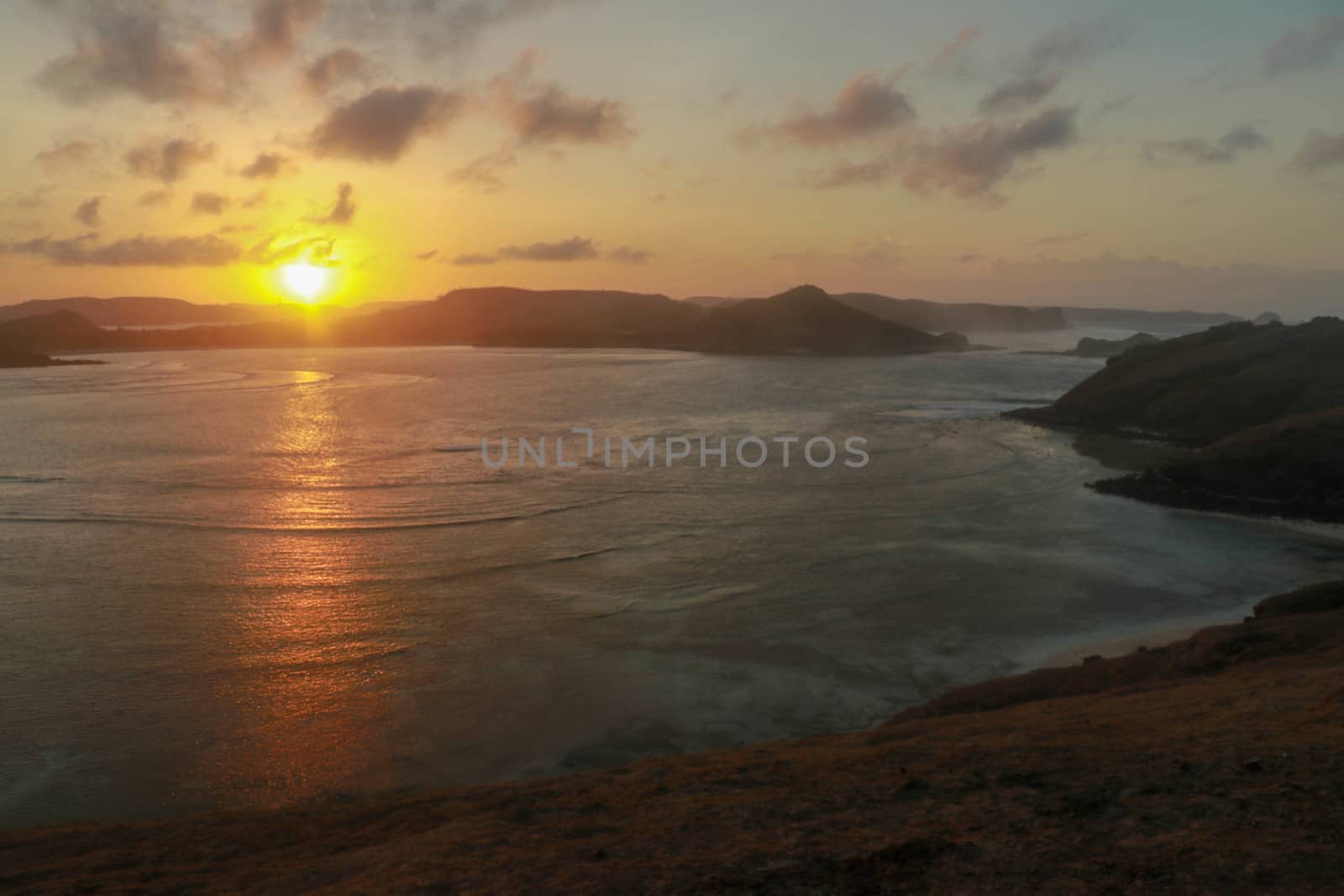 Sunrise view from rock at Tanjung Aan. Rising sun over Tanjung Aan Bay, Lombok, Indonesia. Reflection of the sun's rays on the sea surface. Sunset.