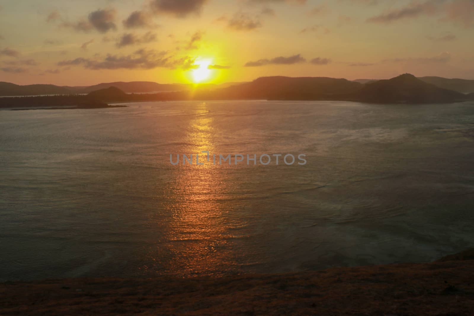 Sunrise view from rock at Tanjung Aan. Rising sun over Tanjung Aan Bay, Lombok, Indonesia. Reflection of the sun's rays on the sea surface. Sunset.