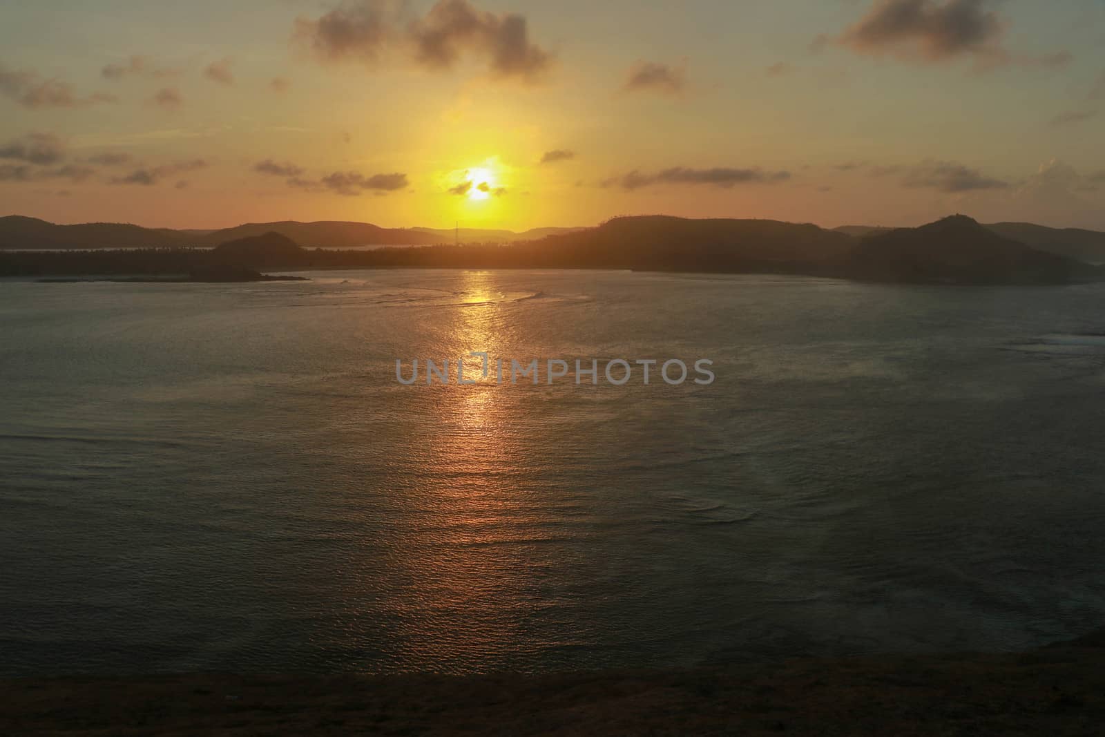 Sunrise view from rock at Tanjung Aan. Rising sun over Tanjung Aan Bay, Lombok, Indonesia. Reflection of the sun's rays on the sea surface. Sunset.