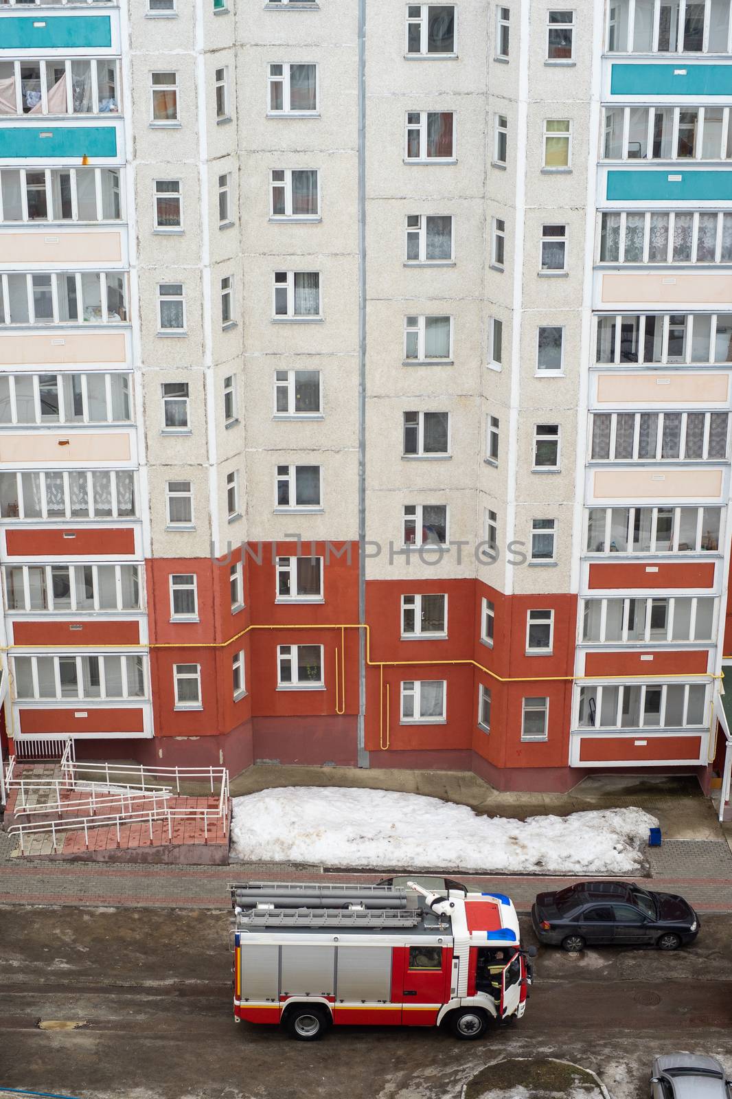 Fire engine in the courtyard of a multi-storey residential building in winter.