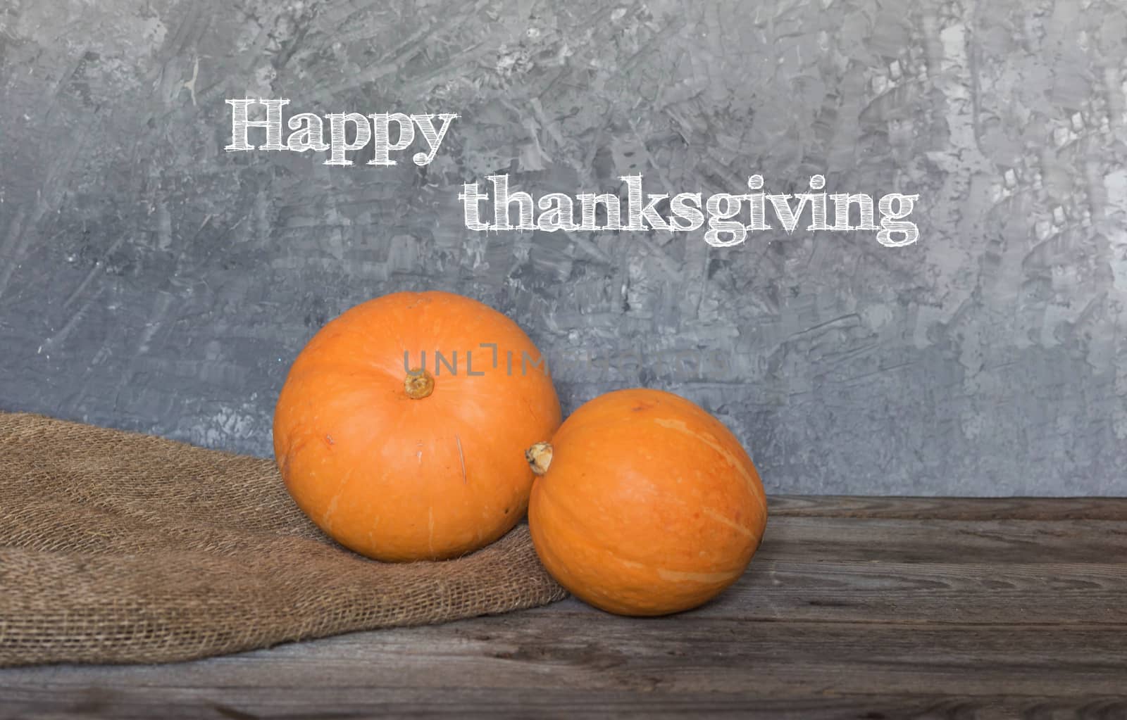 Happy Thanksgiving greeting text with colorful pumpkins over dark wooden and Blackboard background