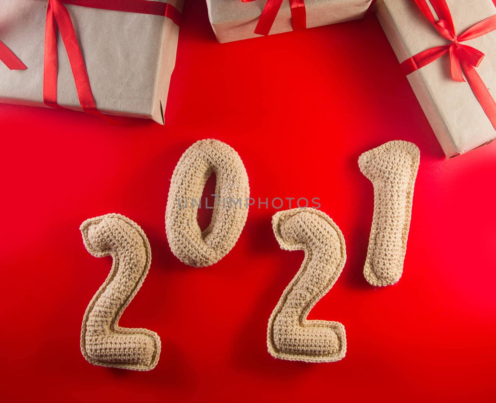 Christmas background with chroched 2021 number and craft paper gift boxes with red ribbons