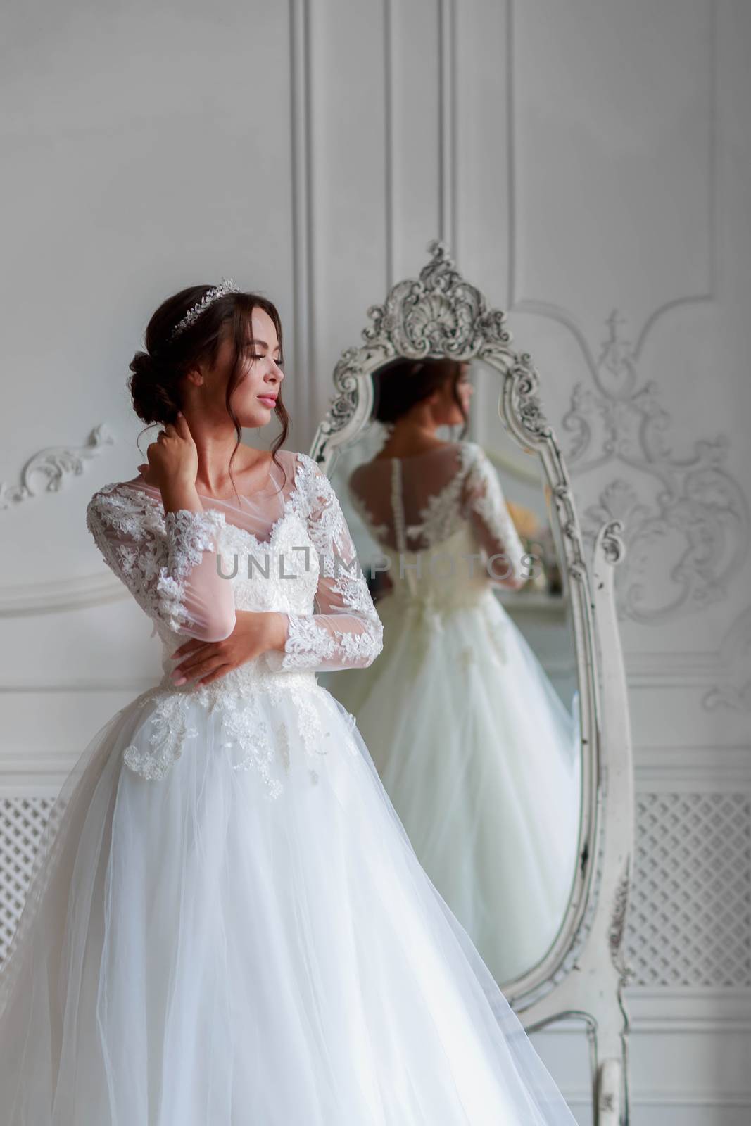 Portrait of a bride in a white wedding dress looks attentively aside.