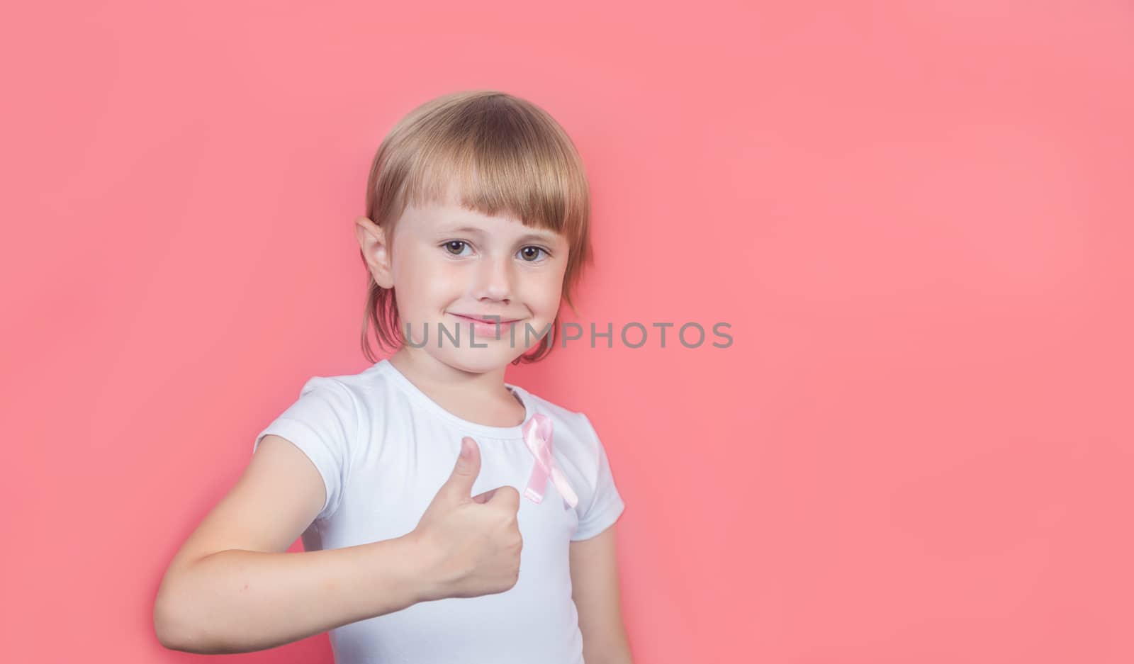 .Little girl showing thumb up wearing white t-shirt and pink breast cancer awareness ribbon
