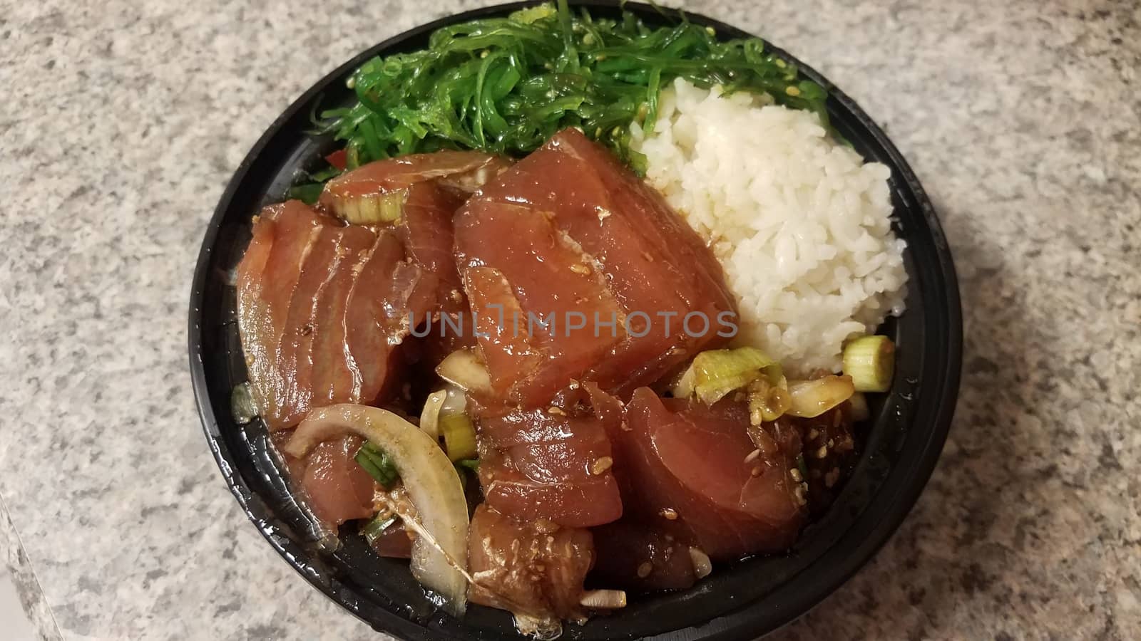 raw tuna and rice and onions in plastic container on counter