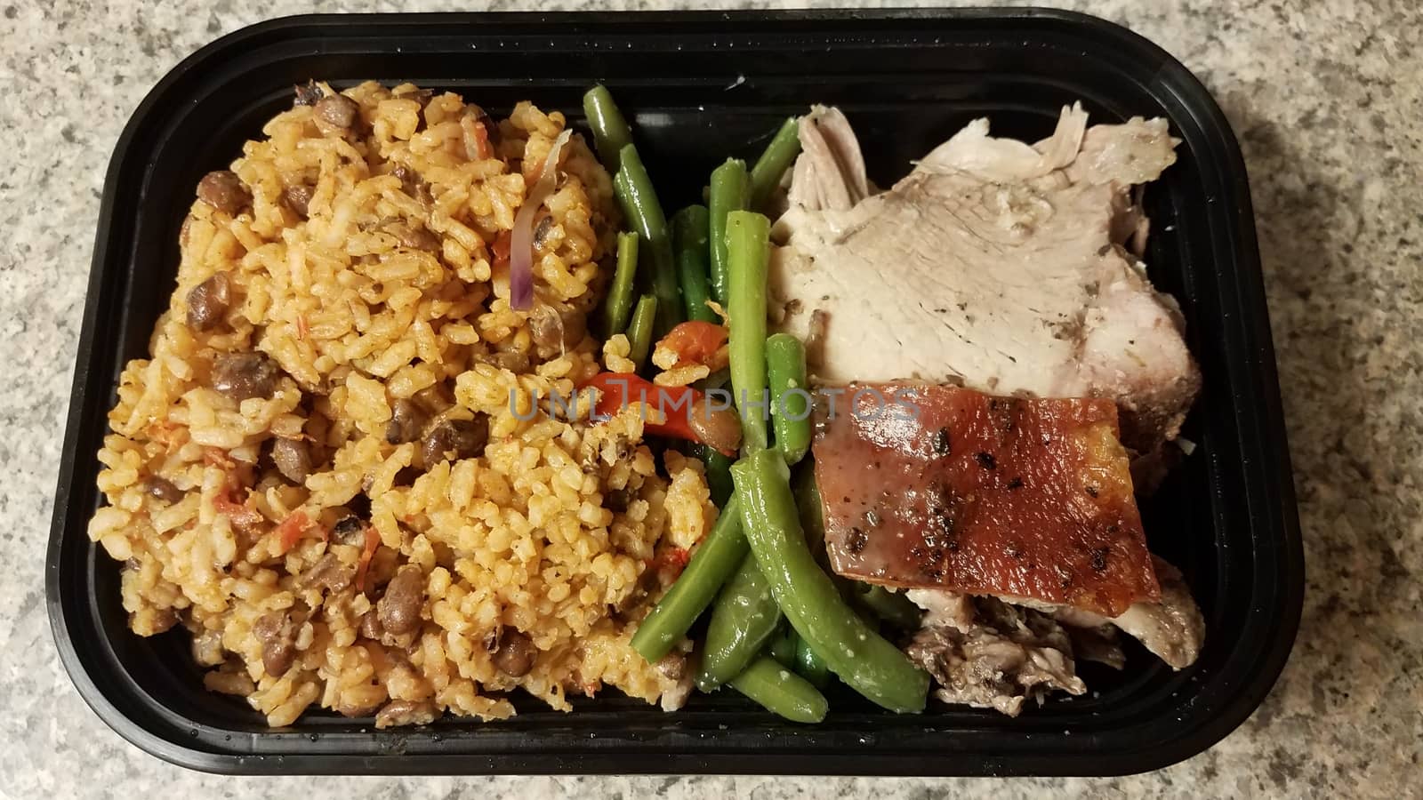 Puerto Rican pork and rice and beans in container on counter