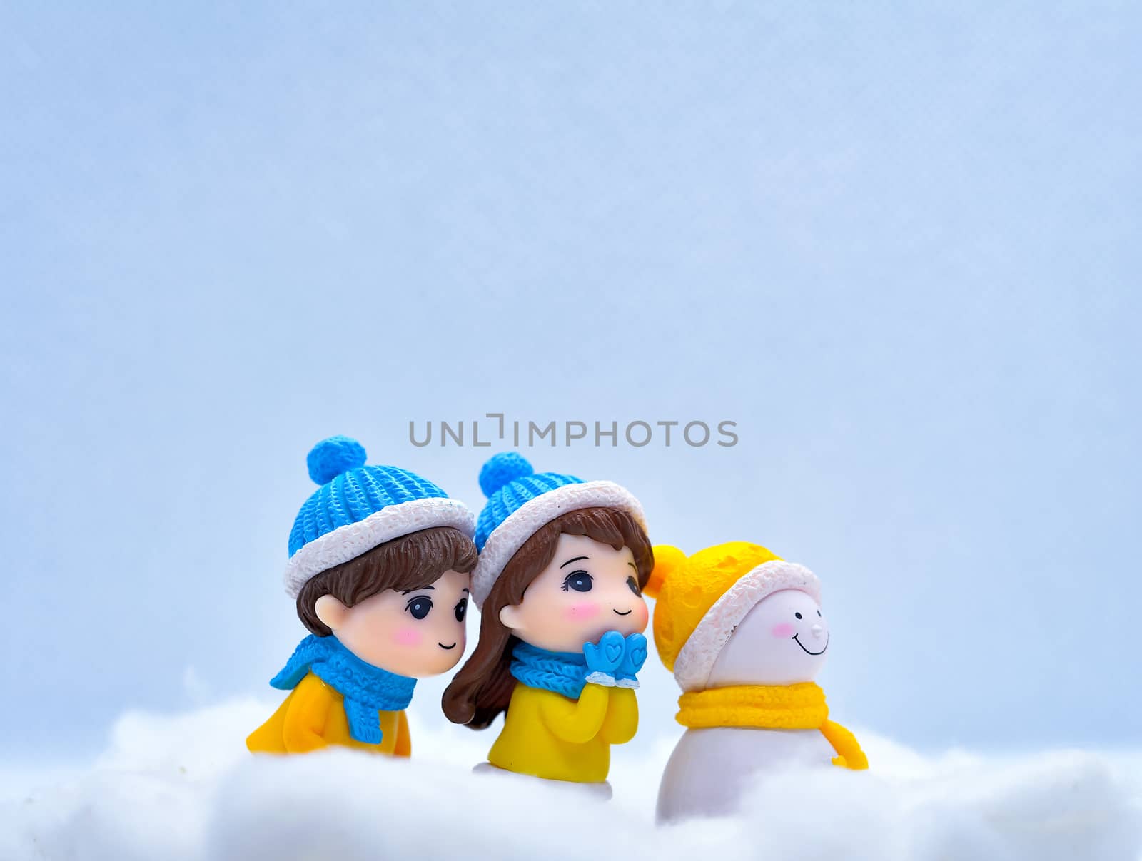 Tourism and travel concept: Miniature people looking for something in winter snow along with little snowman