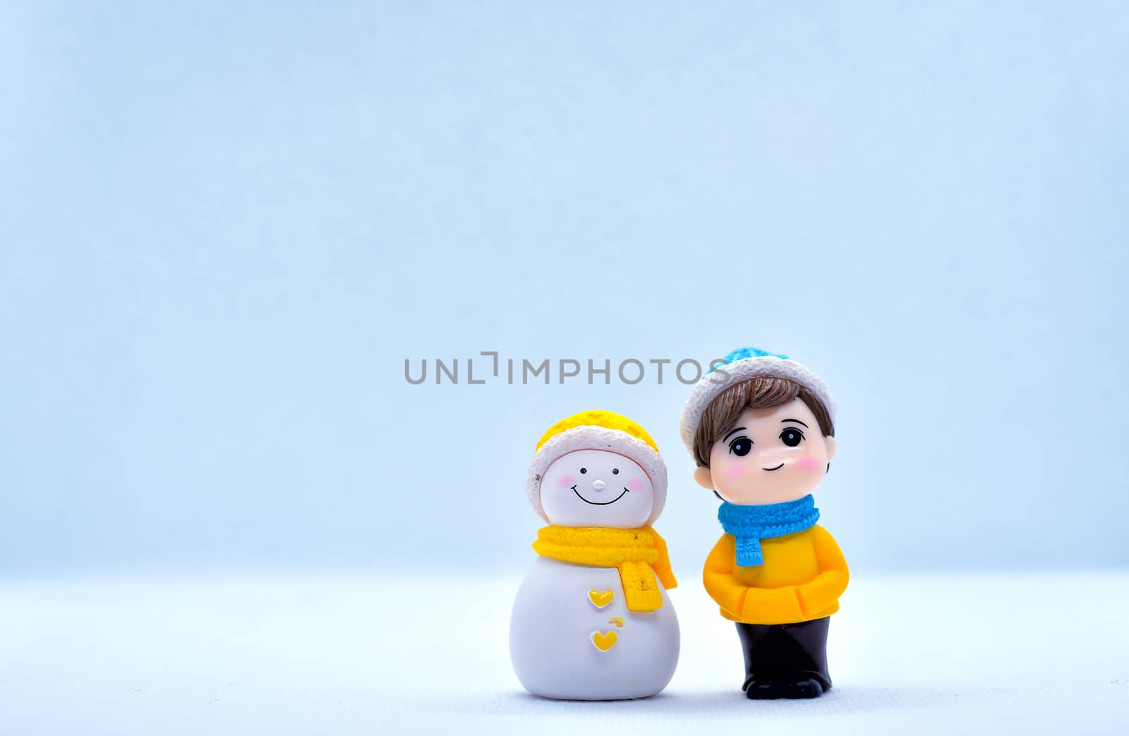 Tourism and travel concept: Miniature little boy and snowman standing in isolated background by rkbalaji