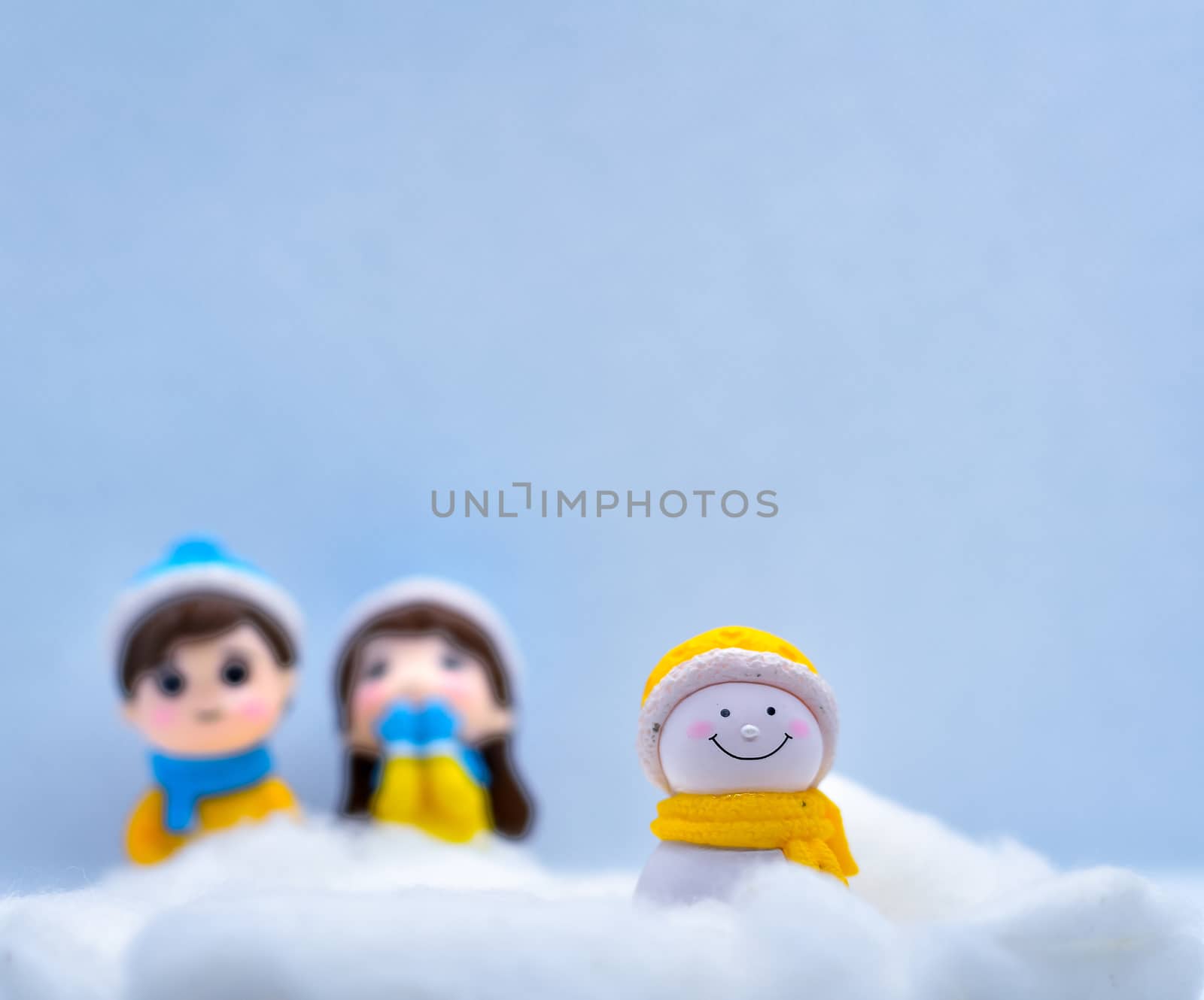 Tourism and travel concept: Miniature little snowman in winter snow with couple in the background