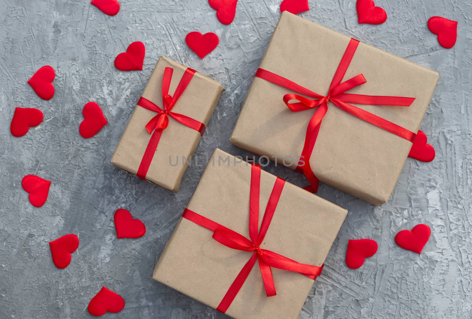 Romantic background with gifts tied with a red ribbon and red hearts on concrete