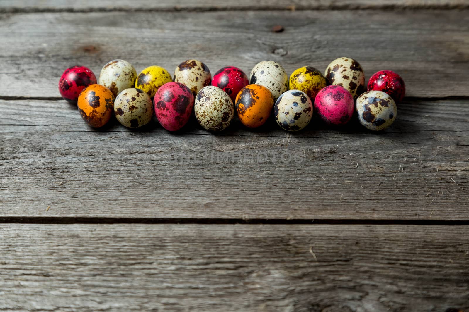 Multi-color dyed easter eggs arranged in a row on wooden background. by galinasharapova