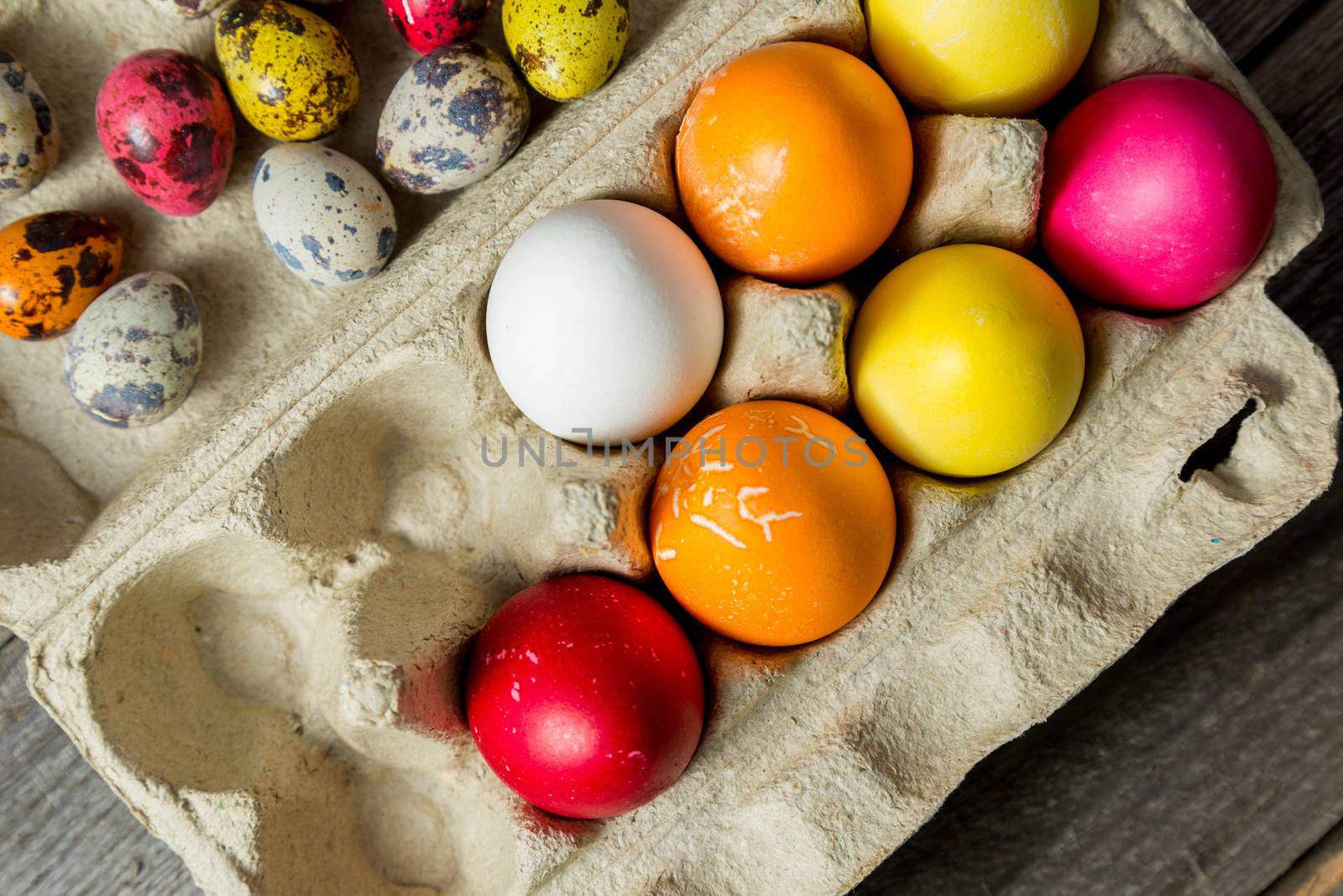 Dyed easter eggs in cardboard box on wooden background. Easter background