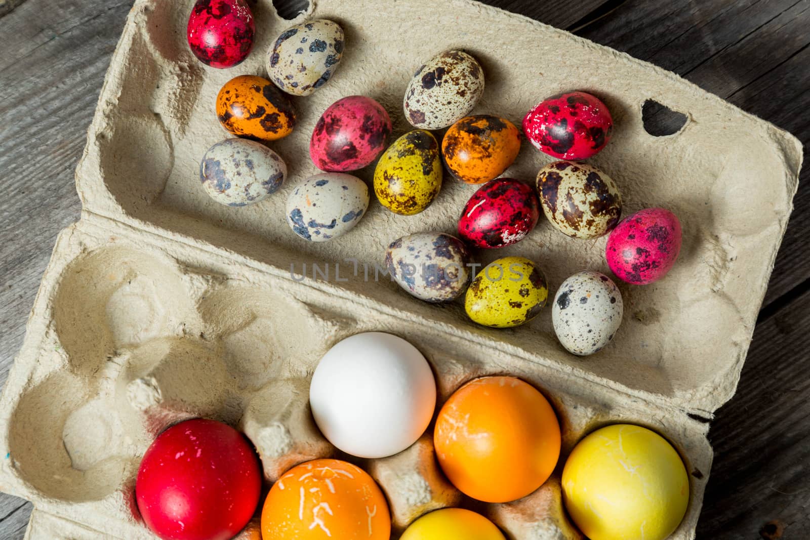 Dyed easter eggs in cardboard box on wooden background. Easter background