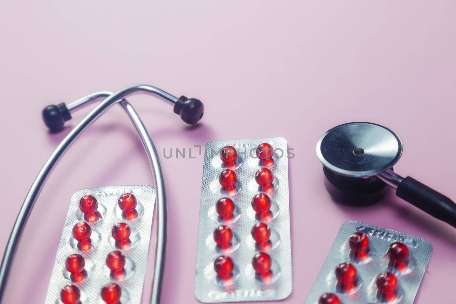 Pills, stethoscope and medical masks on pink background by galinasharapova