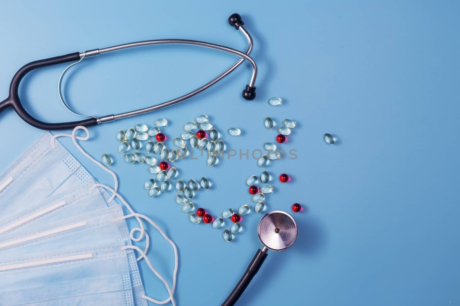 Covid-19, coronavirus treatment. Pills, stethoscope and medical masks on blue background.