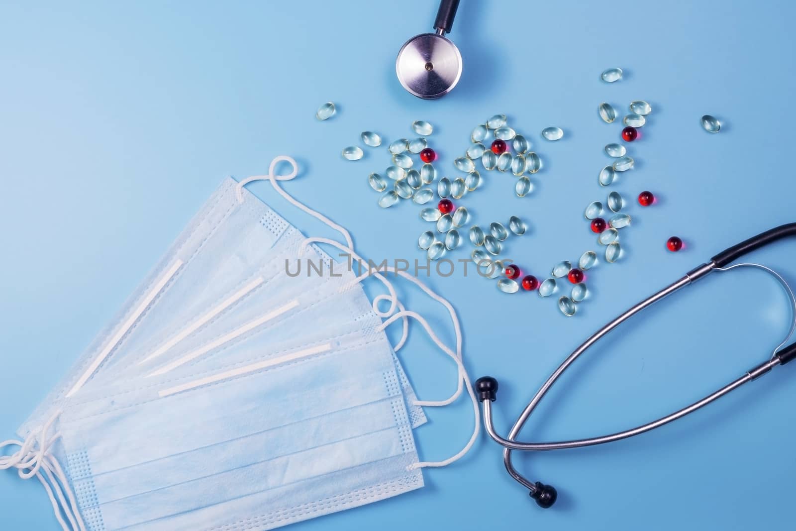 Pills, stethoscope and medical masks on blue background. by galinasharapova
