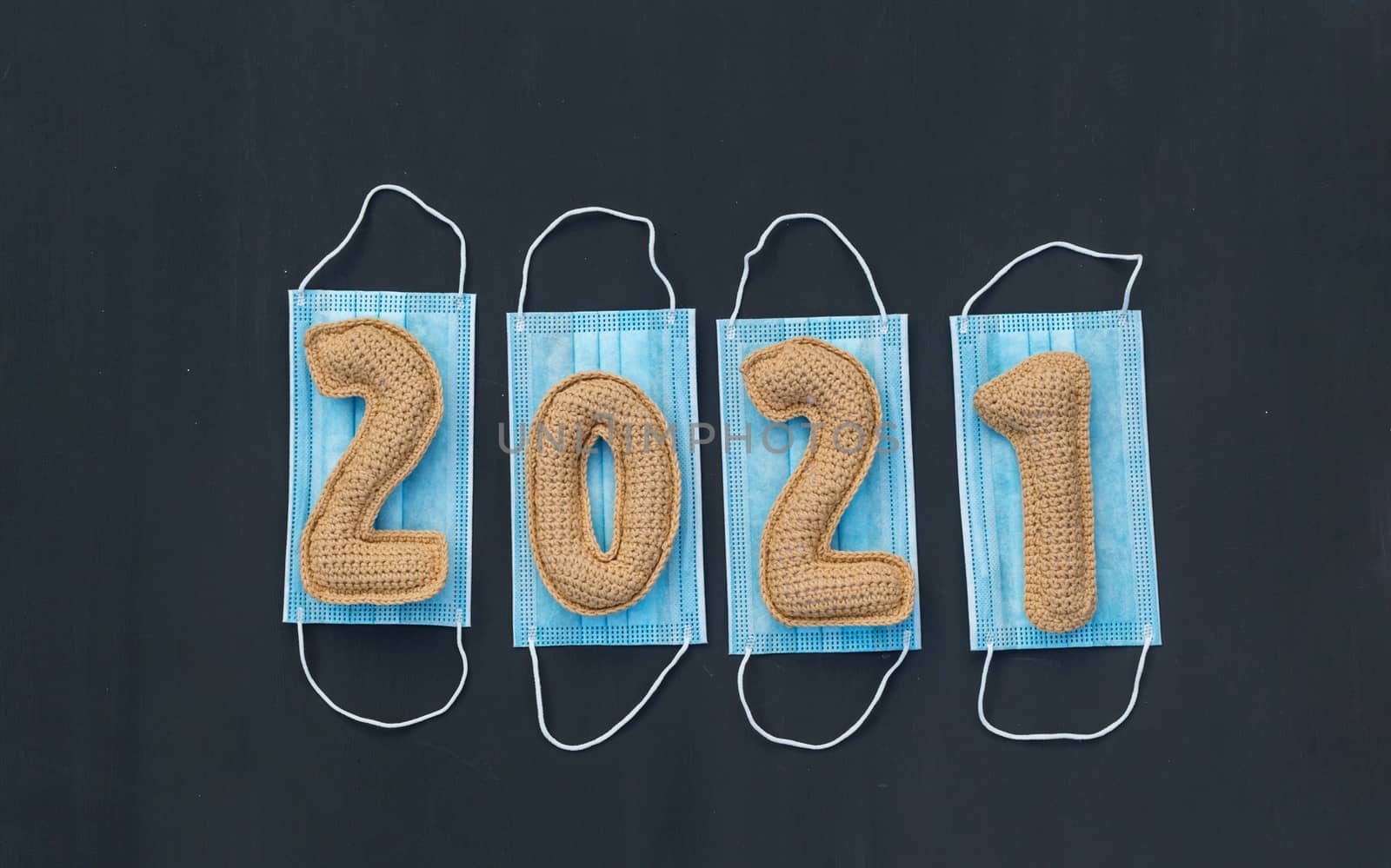 .New year in the context of coronavirus knitted numbers 2021 on medical mask on chalk board