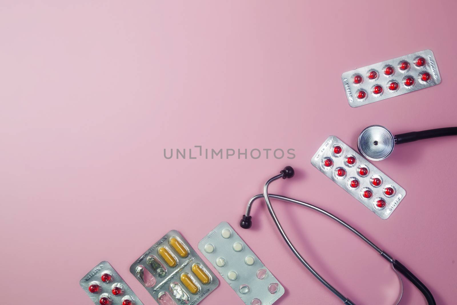 Covid-19, coronavirus treatment. Pills, stethoscope and medical masks on pink background.