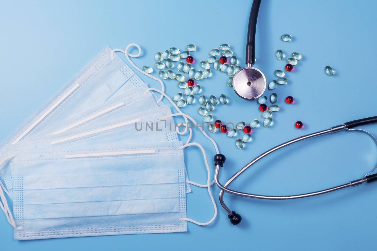 Covid-19, coronavirus treatment. Pills, stethoscope and medical masks on blue background.