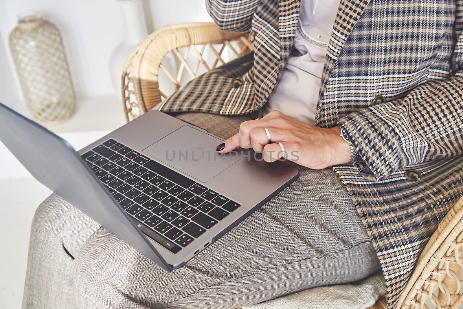 Woman businessman working on laptop in a comfortable rattan wicker chair in the beautiful interior of her country house