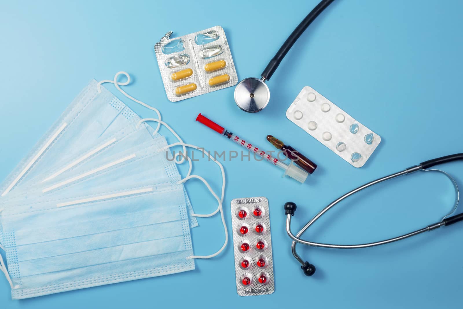 Covid-19, coronavirus treatment. Pills, stethoscope and medical masks on blue background.