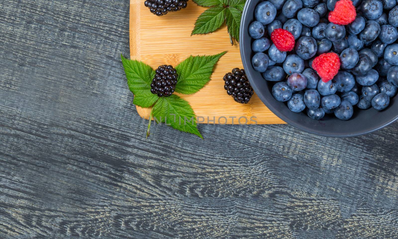 blueberry berry in dark gray ceramic bowl on dark blue wooden background. by galinasharapova